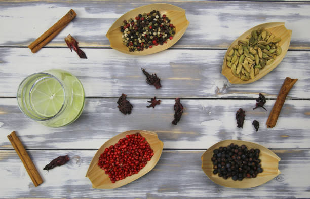 Top down view on white timber plank table with gin tonic glass, red pepper, dried hibiscus flowers,  cinnamon sticks, juniper berries, cardamom natural botanicals ingredients Top down view on white timber plank table with gin tonic glass, red pepper, dried hibiscus flowers,  cinnamon sticks, juniper berries, cardamom natural botanicals ingredients - Germany juniperus chinensis stock pictures, royalty-free photos & images