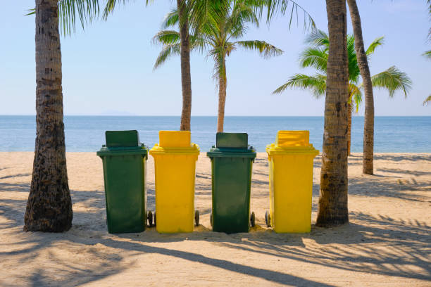 Green and yellow garbage containers installed on a tropical beach. Trash bins . Beach cleaning .
