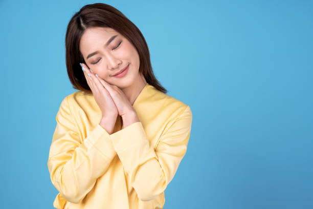 istock Young Asian woman standing and sleeping, isolated on a blue background. 1293771905