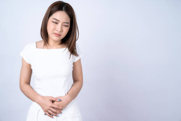 腹痛に苦しむアジアの女性, 白い背景に孤立. - 月経前症候群 ストックフォトと画像