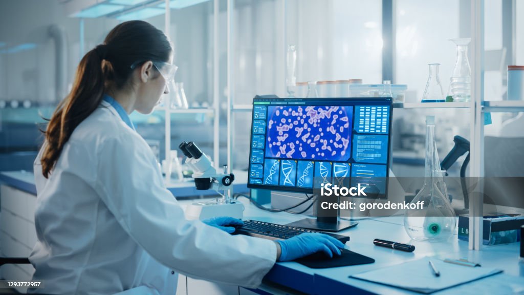 Medical Science Laboratory with Diverse Multi-Ethnic Team of Biotechnology Scientists Developing Drugs, Microbiologist Working on Computer with Display Showing Gene Editing Interface. Biotechnology Stock Photo