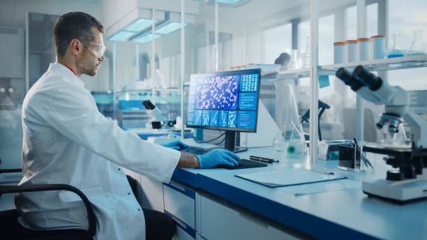 istock Medical Science Laboratory: Microbiologist Working on Computer with Display Showing Gene Editing Interface. Diverse Multi-Ethnic Team of Biotechnology Scientists Developing Drugs. 1293772964