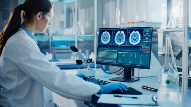 medical science laboratory with diverse multi-ethnic team of biotechnology scientists developing medicines, neurobiologist working on computer with display showing neuroimaging of a brain with scans - laboratory doctor white collar worker research imagens e fotografias de stock
