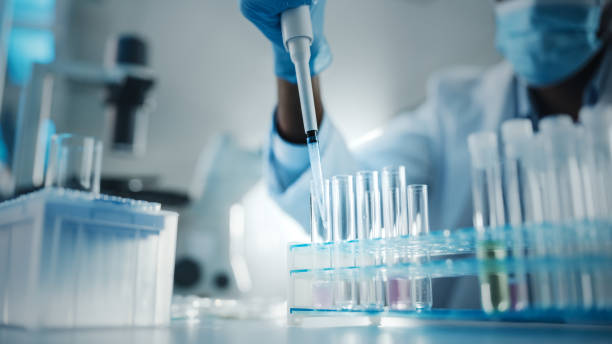 istock Medical Development Laboratory: Black Scientist wearing Face Mask Uses Micro Pipette, Filling Test Tube with Liquid, Conducting Experiment. Pharmaceutical Lab with Medicine, Biotechnology Researchers 1293772987