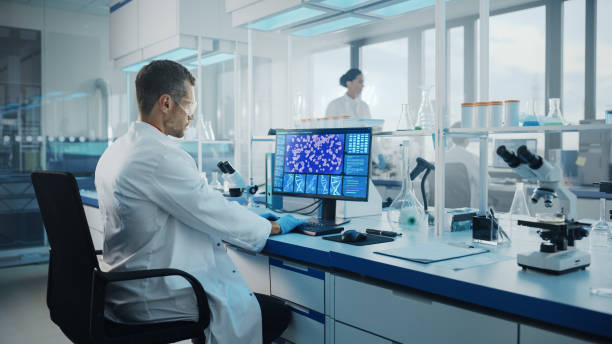 istock Medical Science Laboratory: Microbiologist Working on Computer with Display Showing Gene Editing Interface. Diverse Multi-Ethnic Team of Biotechnology Scientists Developing Drugs. 1293773024