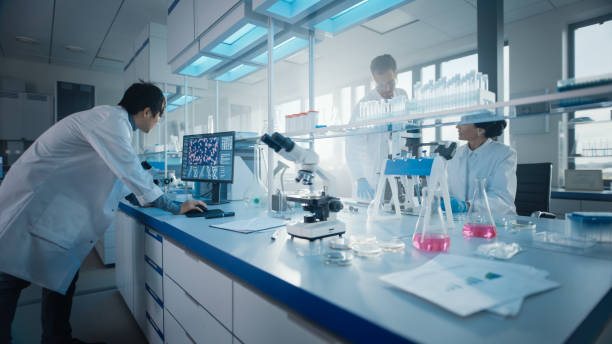 istock Medical Science Laboratory with Diverse Multi-Ethnic Team of Biochemistry Scientists Developing Drugs, Medicine, Doing Biotechnology Research. Working on Computer, Using Microscope, Analysing Samples 1293773571