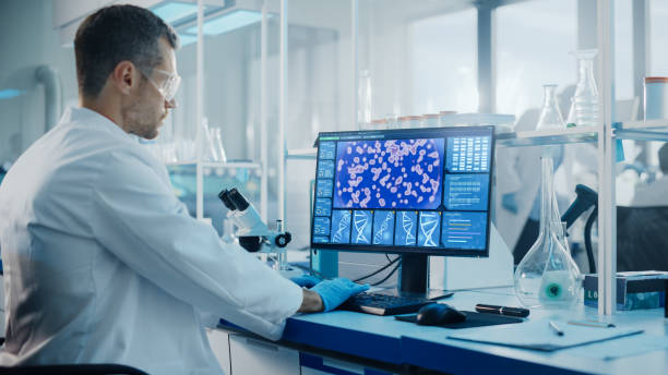 istock Medical Science Laboratory with Diverse Multi-Ethnic Team of Biotechnology Scientists Developing Drugs, Microbiologist Working on Computer with Display Showing Gene Editing Interface. 1293773572