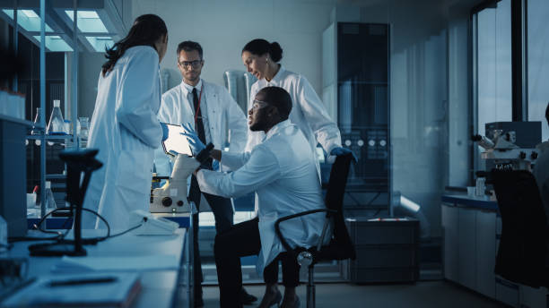 laboratorio di scienze mediche con diversi team multietnici di scienziati di microbiologia si incontrano sullo sviluppo di farmaci, medicina, ricerca biotecnologica. lavorare sui computer, analizzare esempi - laboratorio foto e immagini stock