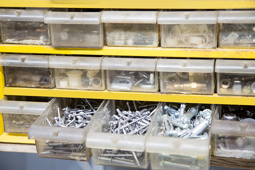 Small drawers in plastic case holding an assortment of items.  Screws, clamps, parts, bolts, nails and odd items useful to a handyman.