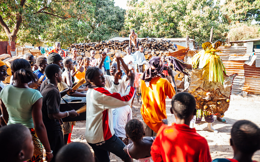 Serrekunda, Gambia - Local celebration is going on in dusty backstreets of Serrekunda, young people playing drums and some are dancing in special costumes.