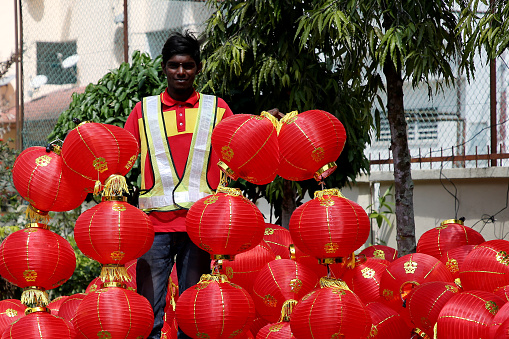 Portrait of Indian ethnicity young man holding abundance of Chinese lanterns to be installed surrounding Thean Hou Temple, Kuala Lumpur Malaysia.