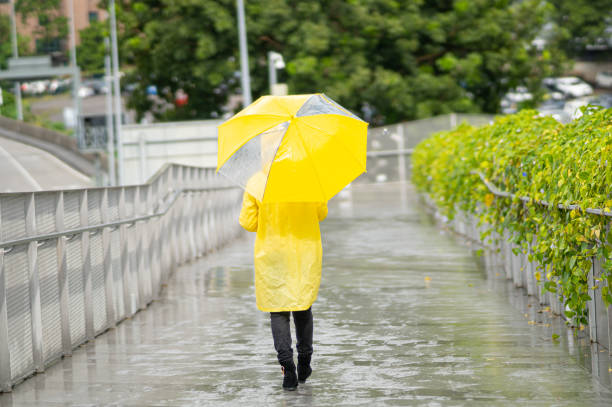Cute Asian girl wearing yellow rain coat during raining day