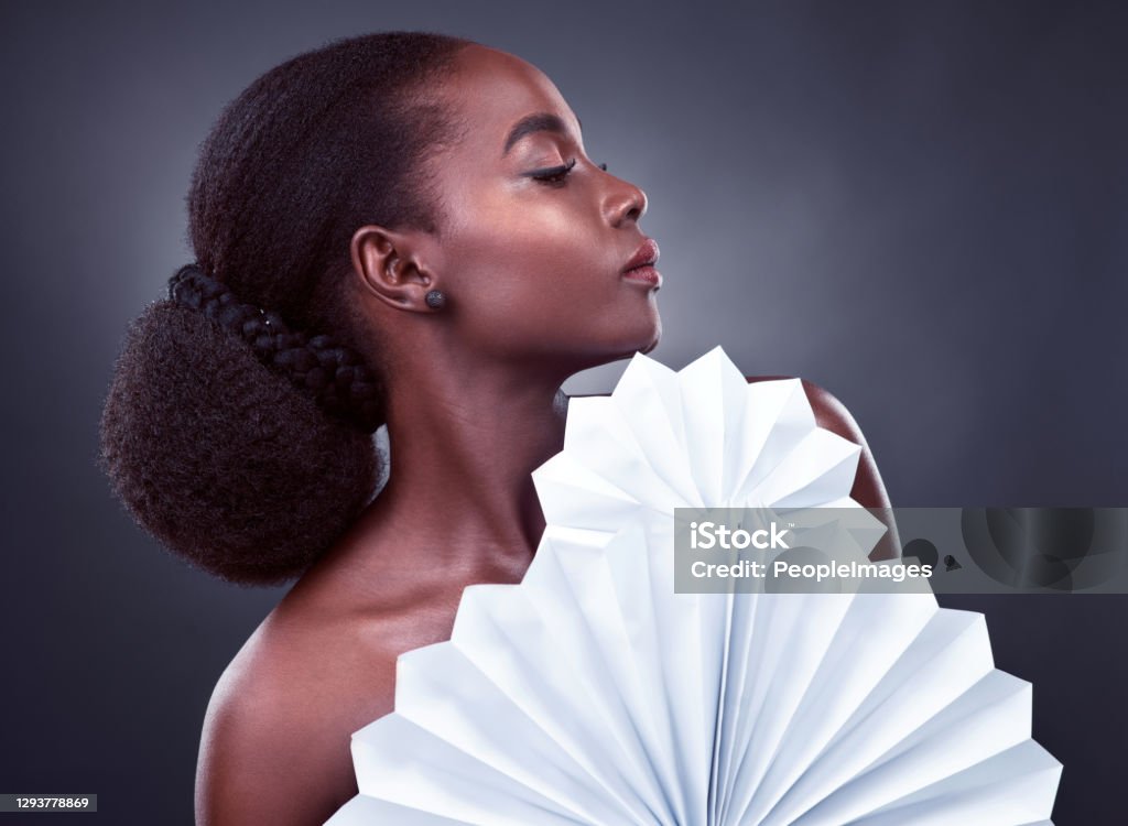 Beauty is someone who is unafraid to be herself Studio shot of a beautiful young woman posing with origami fans against a black background Avant-Garde Stock Photo