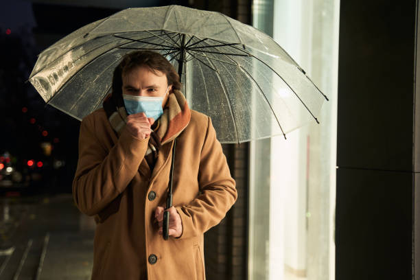 istock Man wearing protective mask walking under the transparent umbrella 1293782081