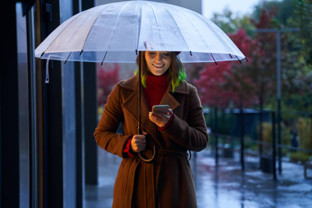 istock Girl outdoor with umbrella using smart phone 1293782171