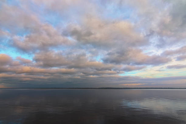 istock Abstract wide-angle landscape view of tranquil water space. Picturesque cloudy sky reflected in the water. Winter sunset view 1293782673