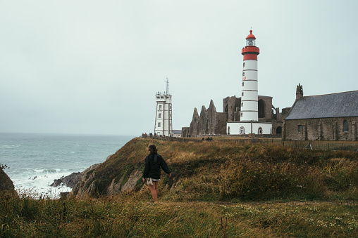 Plougonvelin, France - July 29, 2018: Woman at the cliffs of Pointe Saint Mathieu in Brittany, France. Cloudy day