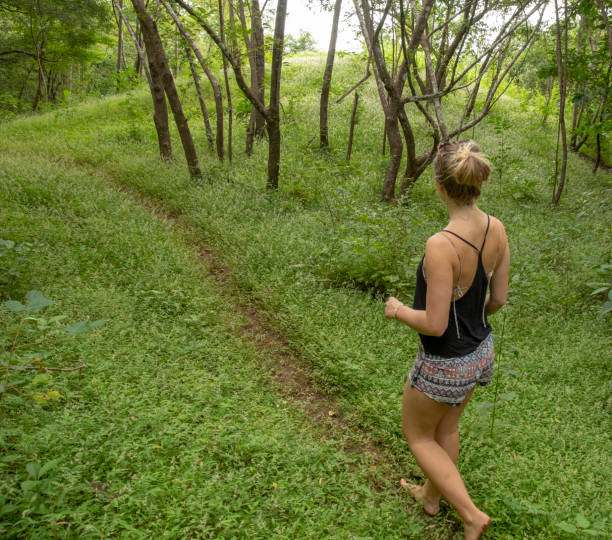 istock Young woman walks down forested trail in the morning 1293785679