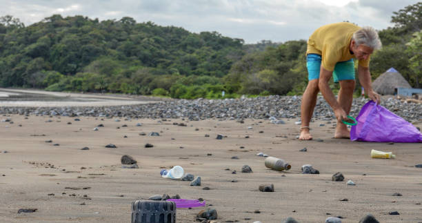 istock Man picks up garbage on beach in the morning 1293786620