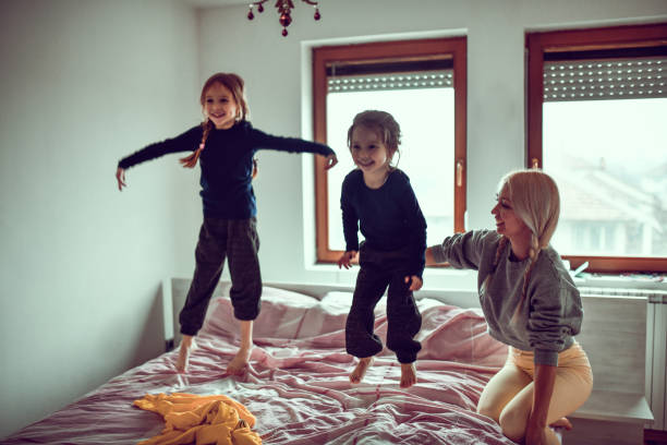 istock Mother Enjoying Time Spent With Child Daughters Jumping On Bed 1293787650