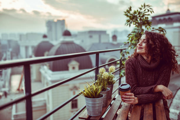 istock Female Enjoying Coffee On Building Rooftop Looking At View 1293788691