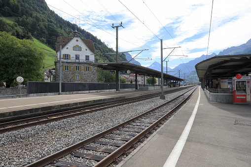 Fluelen, Switzerland - August 25, 2020: There is no train at the train station. There are people on the platform waiting for the train.