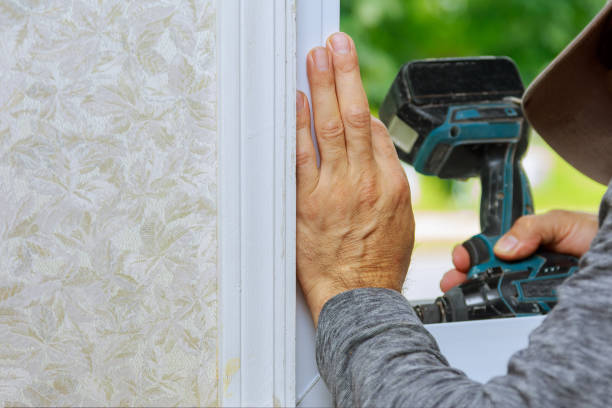 istock Worker installing of the plastic new window during home renovation uses an electric drill 1293794827