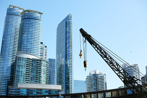 Construction is going on at the waterfront, Toronto, Canada. Cranes are at work. There are a few new high rise buildings in the background. The tiny black dot on the right is a helicopter!