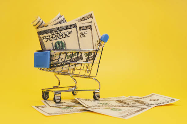 istock Shopping cart with dollars on yellow background. 1293795678