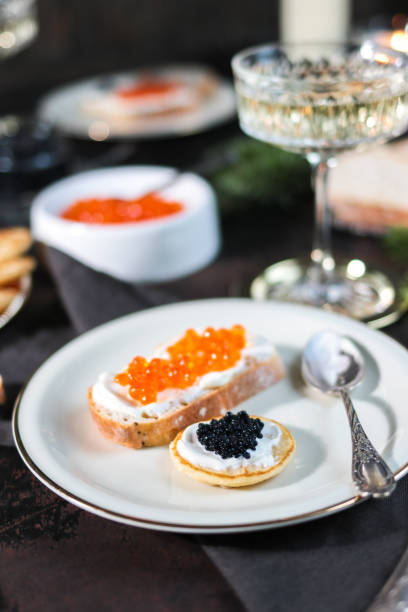 праздничный рождественский стол с икрой блинис и шампанским - appetizer caviar gourmet blini стоковые фото и изображения