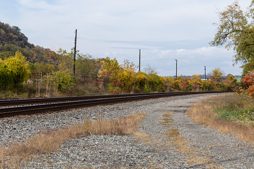 Curved train tracks running through a rural area, fall landscape with autumn leaves, horizontal aspect