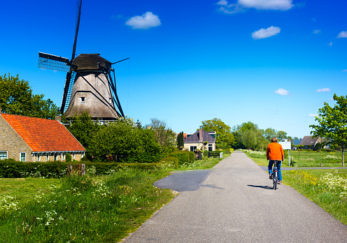 Active senior cyclist in rural area in springtime, windmill. Shot in Friesland.