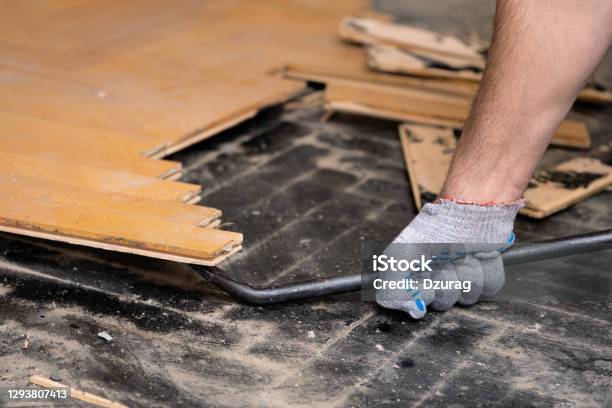 Worker Removes Old Parquet Using A Tire Iron Tool Stock Photo - Download Image Now - Flooring, Removing, Demolishing