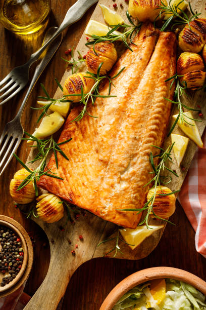 하셀백 감자, 레몬, 신선한 로즈마리를 곁들인 구운 연어 필레가 나무 판에 담겨 있습니다. - salmon cooked pepper plank 뉴스 사진 이미지