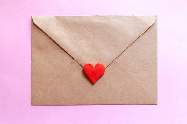 istock Love letter in a craft envelope with clay red heart on pink background. 1293811065
