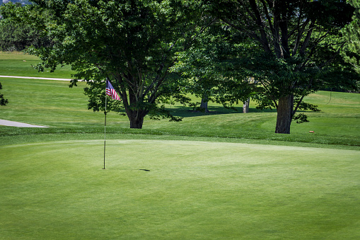 Green on golf course with hole pin American Flag