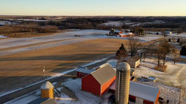 estabelecendo uma cena do meio-oeste no inverno.  vista aérea de estrada rústica, fazendas, fazendas ao longo da rua. campo agrícola coberto de primeira neve, sol ensolarado, luz solar suave ao pôr do sol - winter agriculture ranch field - fotografias e filmes do acervo