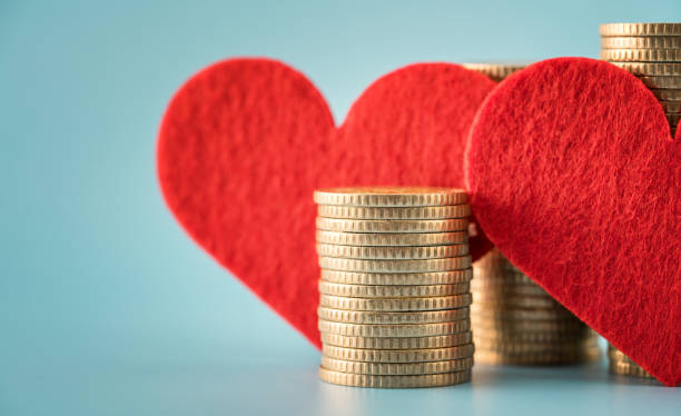 Coin stacks and heart on blue background stock photo