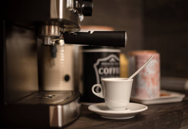 White coffee cup with saucer on kitchen table with modern coffee machine. Modern coffee station at home
