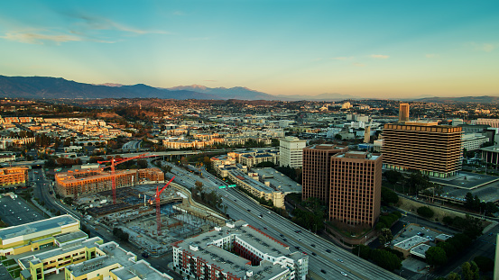 Aerial shot of Los Angeles at sunset, looking down on the 110 freeway heading northeast out of downtown towards Montecito Heights and Highland Park. In the foreground, new apartment buildings are being constructed.