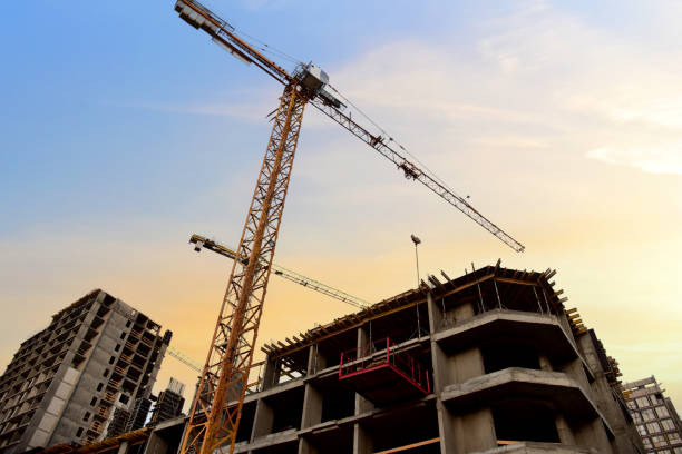 istock Tower crane in action at construction site on blue sky background 1293819448