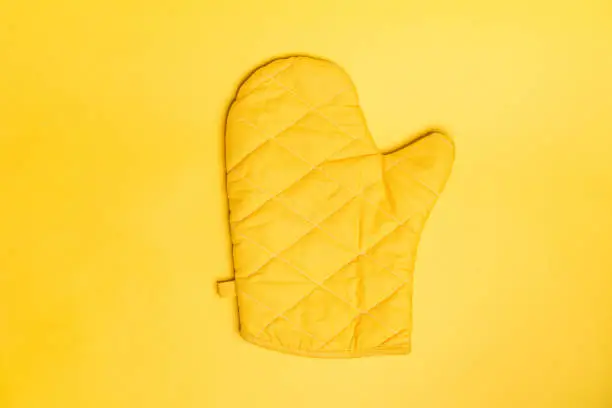 Photo of Top view of yellow oven gloves on yellow color background. Mockup for food banner and kitchen protection equipment.