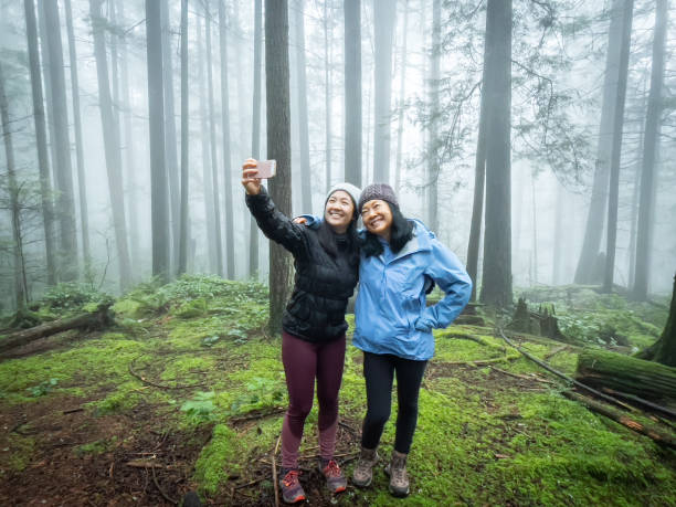 fille eurasienne prenant le selfie avec la mère asiatique dans la forêt brumeuse - mt seymour provincial park photos et images de collection