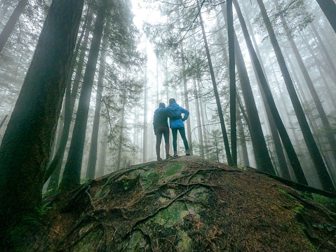 Mature mother and young adult daughter enjoying winter walk through wet forest on Mount Seymour, North Vancouver, British Columbia, Canada