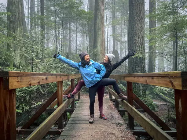 Photo of Asian Mother and Eurasian Daughter Posing on Bridge in Forest