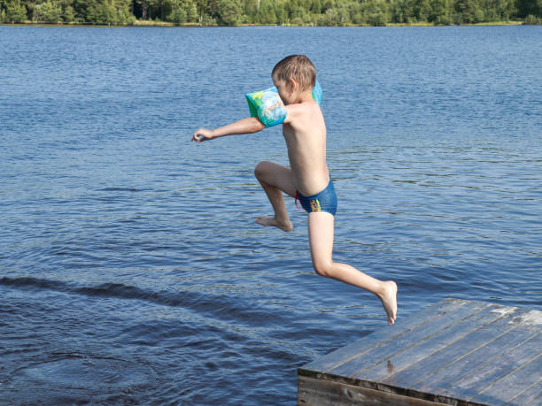 istock Boy jumping into the lake from jetty 1293851424