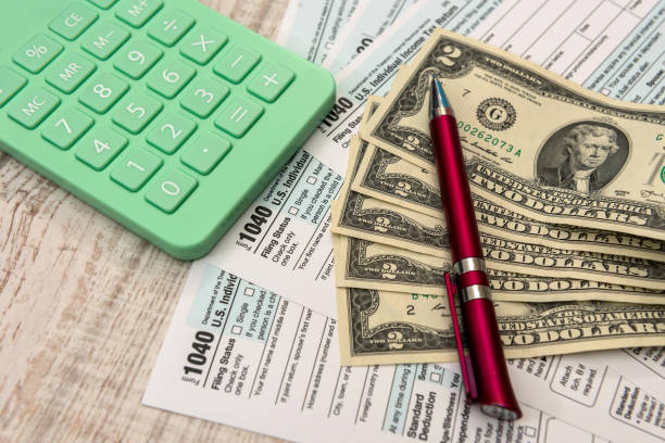 istock Financial document us 1040 tax forms with dollars, calculator and pen 1293854343