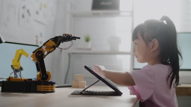 デジタルタブレット上の女の子制御ロボットアーム、高校でロボット工学のレッスンを取得