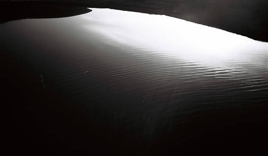 Sunset reflections on a river mouth flowing into the sea, black and white 35mm