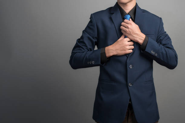 fermez-vous vers le haut de l’homme d’affaires dans le procès bleu utilisant une cravate sur le fond gris - suit necktie close up gray photos et images de collection